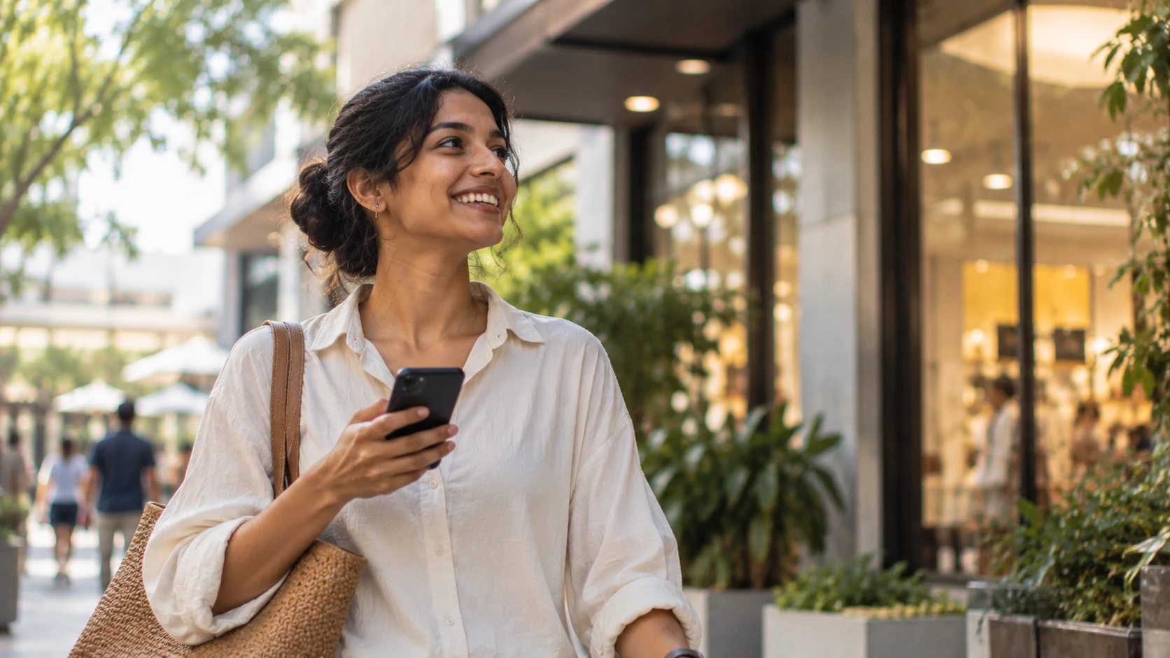 A smiling woman walking down a street with her phone in hand